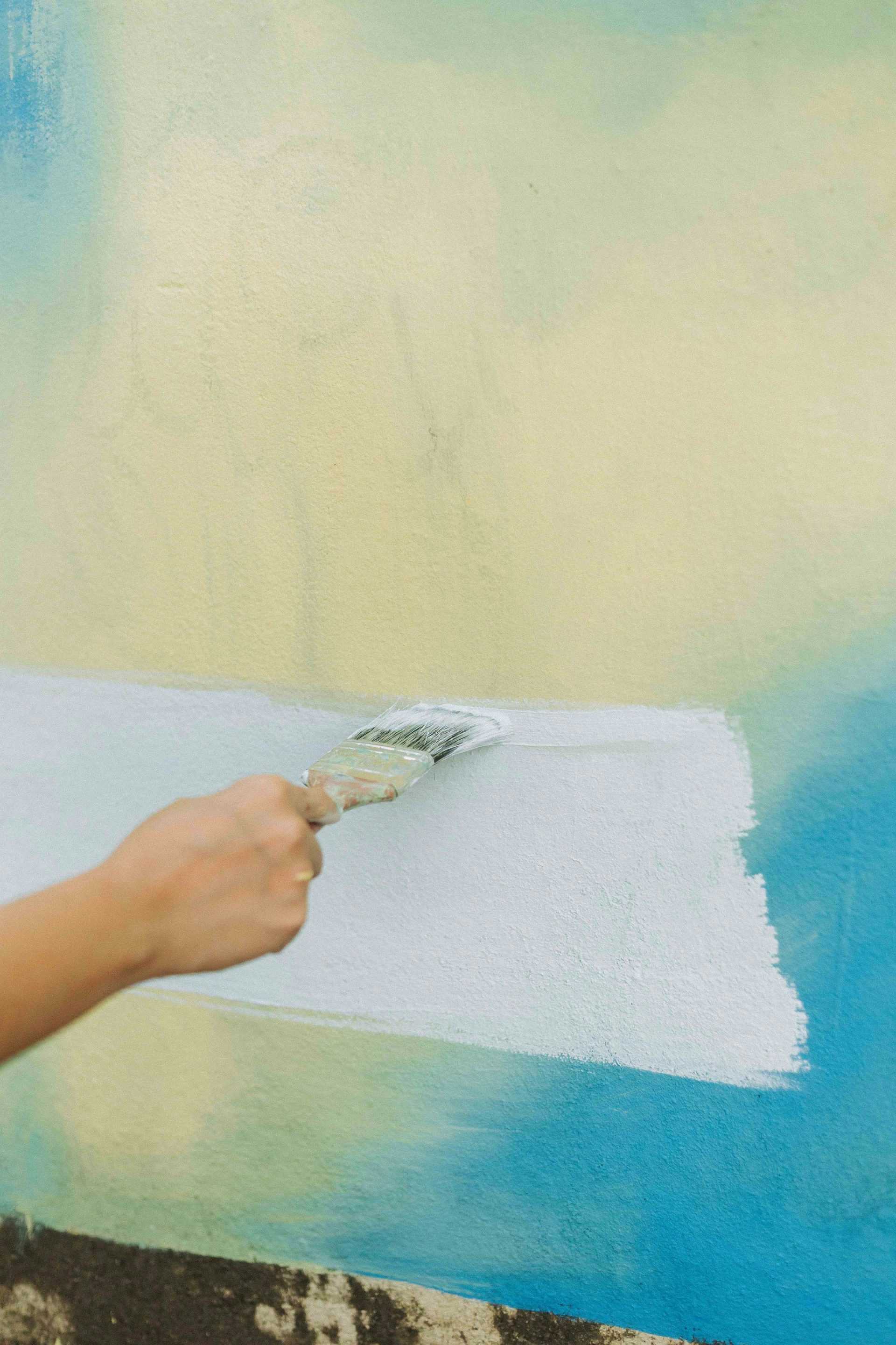 eine Person, die eine Wand mit einer Farbrolle streicht